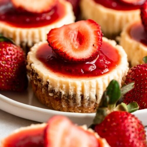 Mini strawberry cheesecakes on a plate.