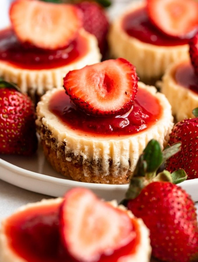 Mini strawberry cheesecakes on a plate.