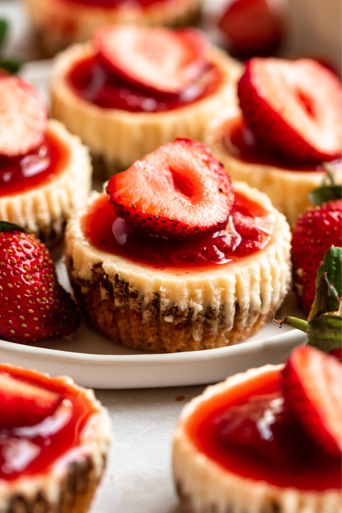 Mini strawberry cheesecakes on a plate.