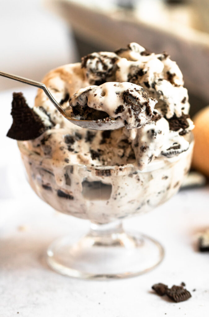 Spoon scooping oreo ice cream from an ice cream bowl.