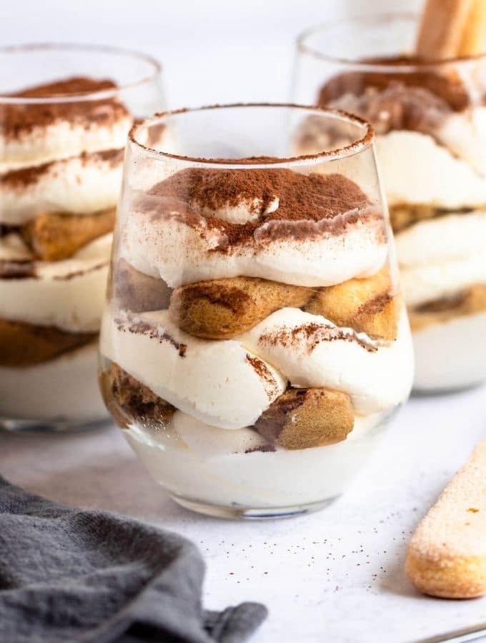 Three tiramisu cups on a white backround.