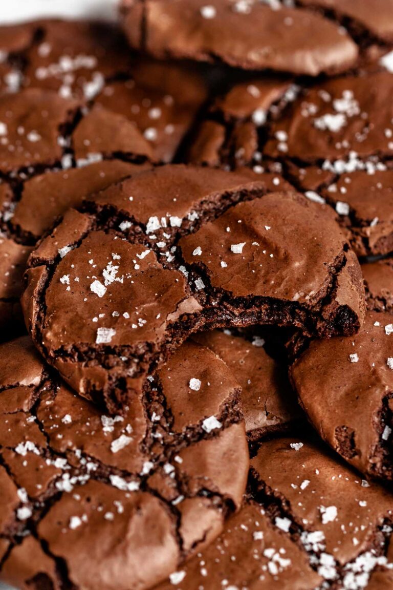 Chocolate crinkle cookies dusted with powdered sugar, stacked in a pile showing fudgy texture.
