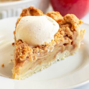 Slice of apple crumble pie with a scoop of vanilla ice cream on top.