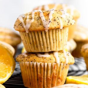Stack of two lemon poppy seed muffins with lemon glaze on top.