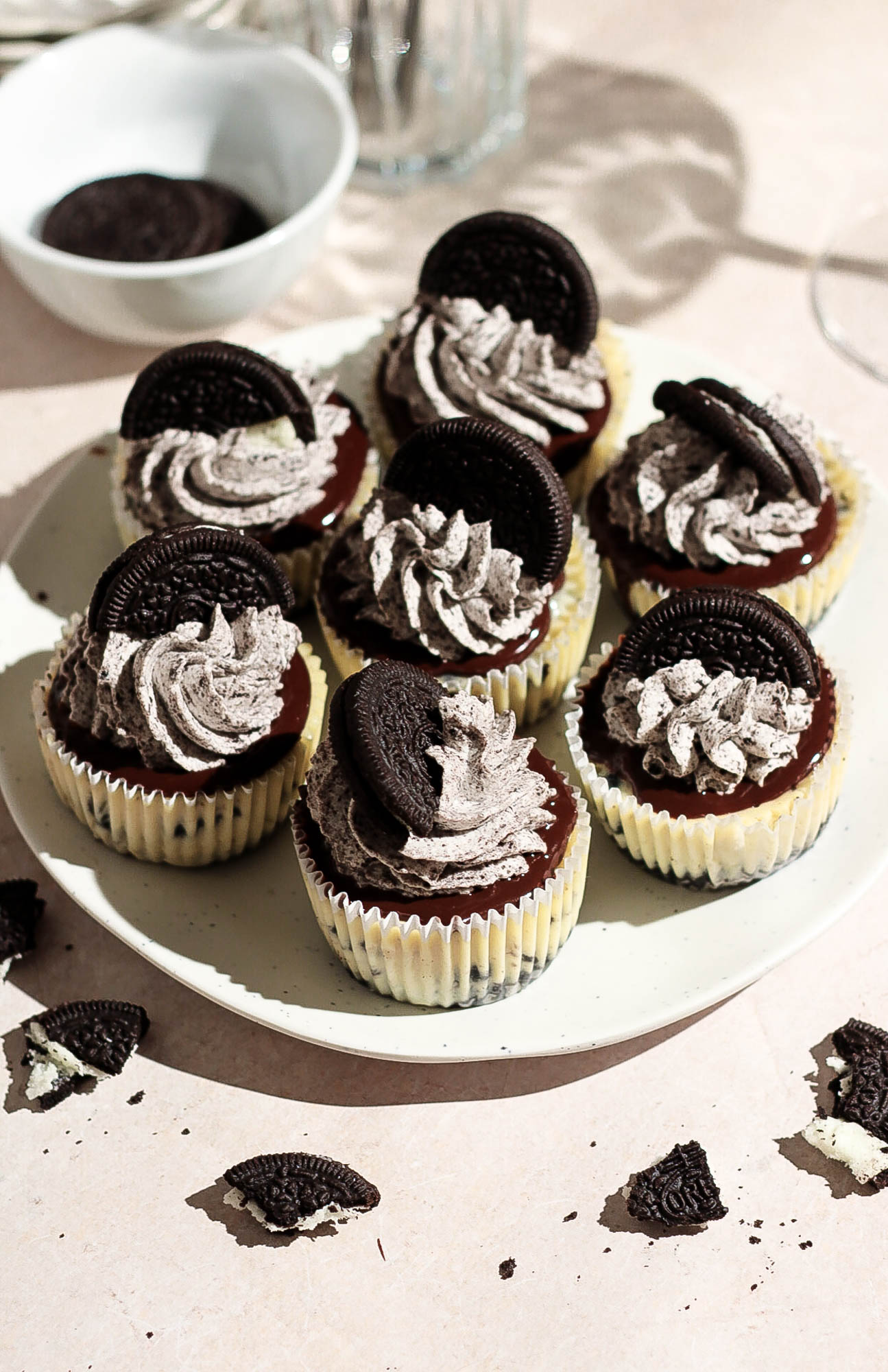 Overhead view of a plate filled with mini Oreo cheesecakes featuring layers of crust, filling, and cookie toppings