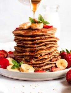 Stack of protein pancakes with maple syrup drips.