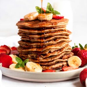 Stack of protein pancakes with maple syrup drips.
