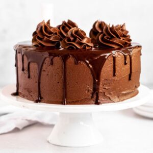 Triple chocolate cake on a white cake platter.