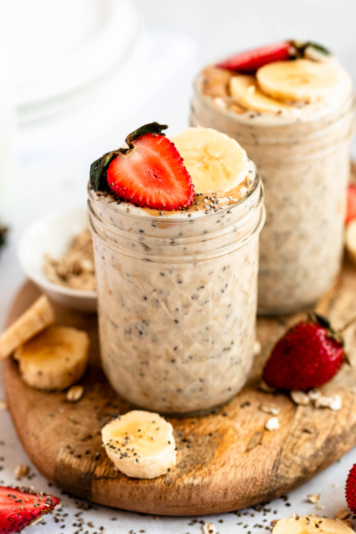 Close up shot of high protein overnight oats in two jars with strawberries and bananas.