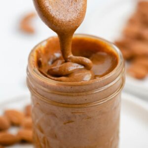 Almond butter in a jar with a wooden spoon.