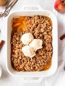 Overhead shot of peach crisp with canned peaches with vanilla ice cream.