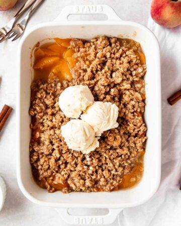 Overhead shot of peach crisp with canned peaches with vanilla ice cream.