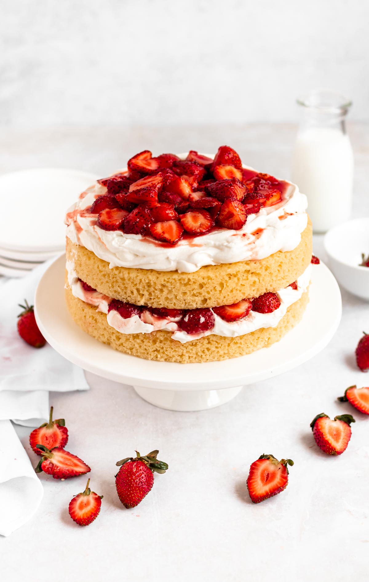 Whipped cream strawberry vanilla cake on a cake platter.