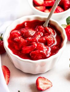 Strawberry topping for cheesecake in a white bowl.
