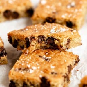 Close up shot of two chocolate chip blondies with the top one missing a bite.
