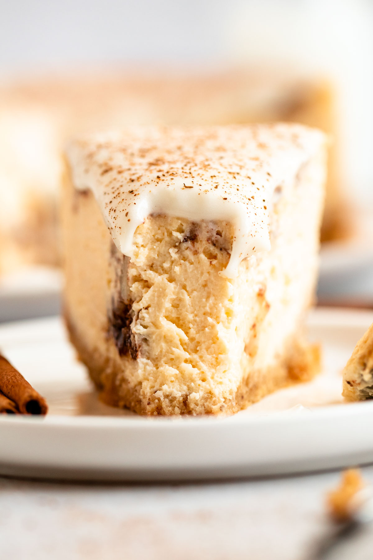Close up shot of a slice of cinnamon roll cheesecake with a bite missing.