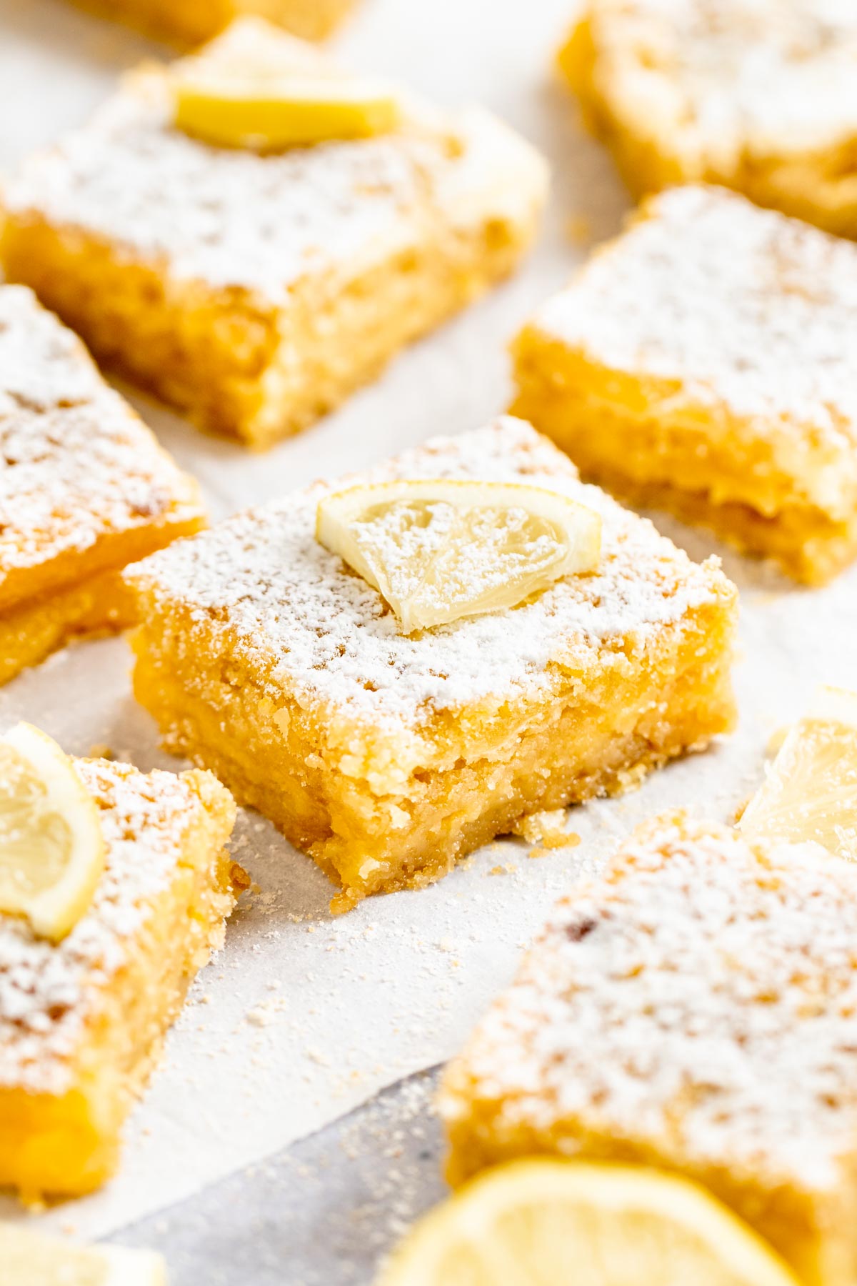 Slices of lemon bars with graham cracker crust on parchment paper.