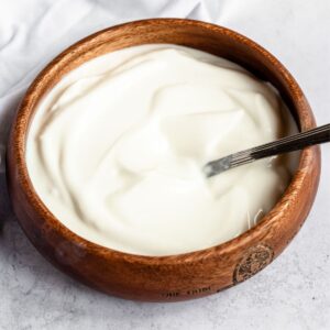 Yogurt in a wooden bowl with a spoon.