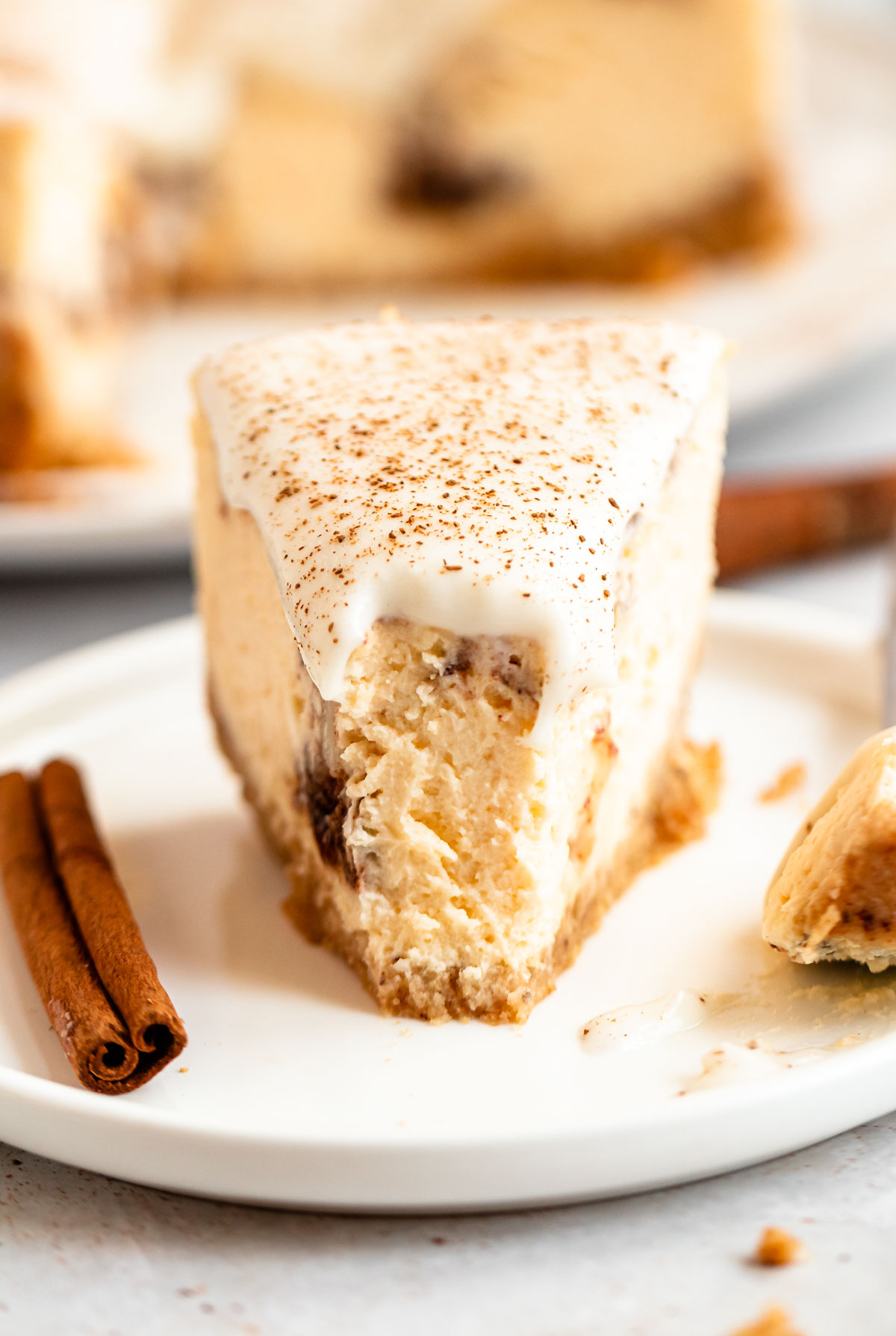 Close up shot of a slice of cinnamon roll cheesecake with a bite missing.