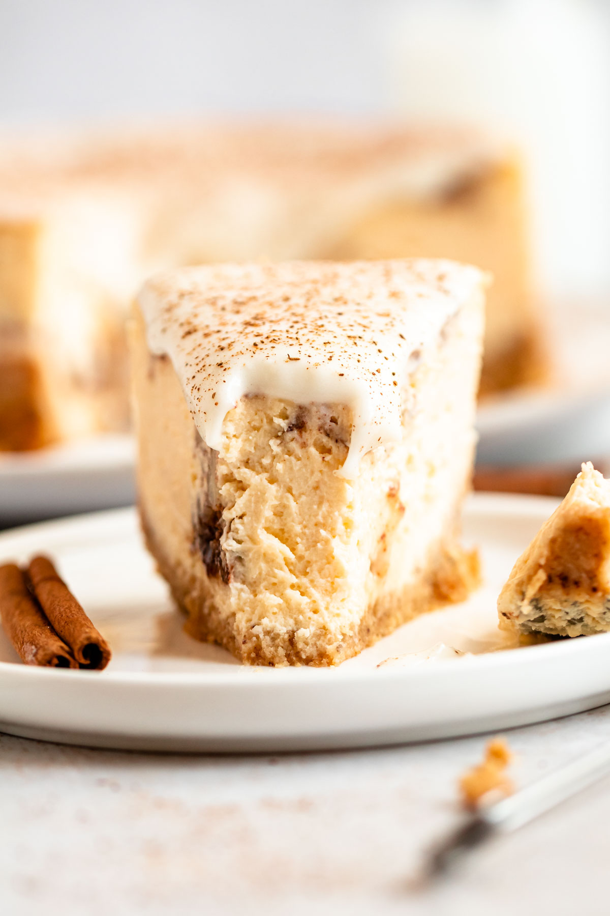 Close up shot of a slice of cinnamon roll cheesecake with a bite missing.