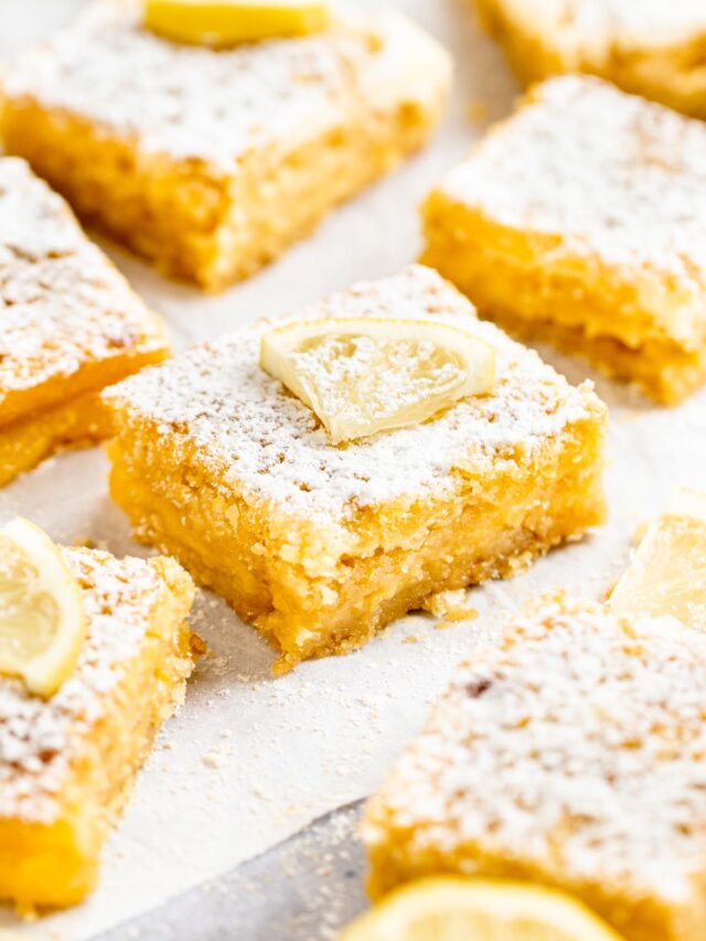 Slices of lemon bars on parchment paper.