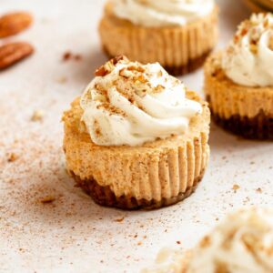 Mini pumpkin cheesecakes with whipped cream and cinnamon on top.