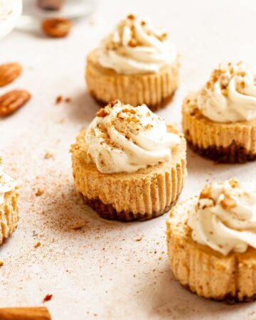 Mini pumpkin cheesecakes with whipped cream and cinnamon on top.