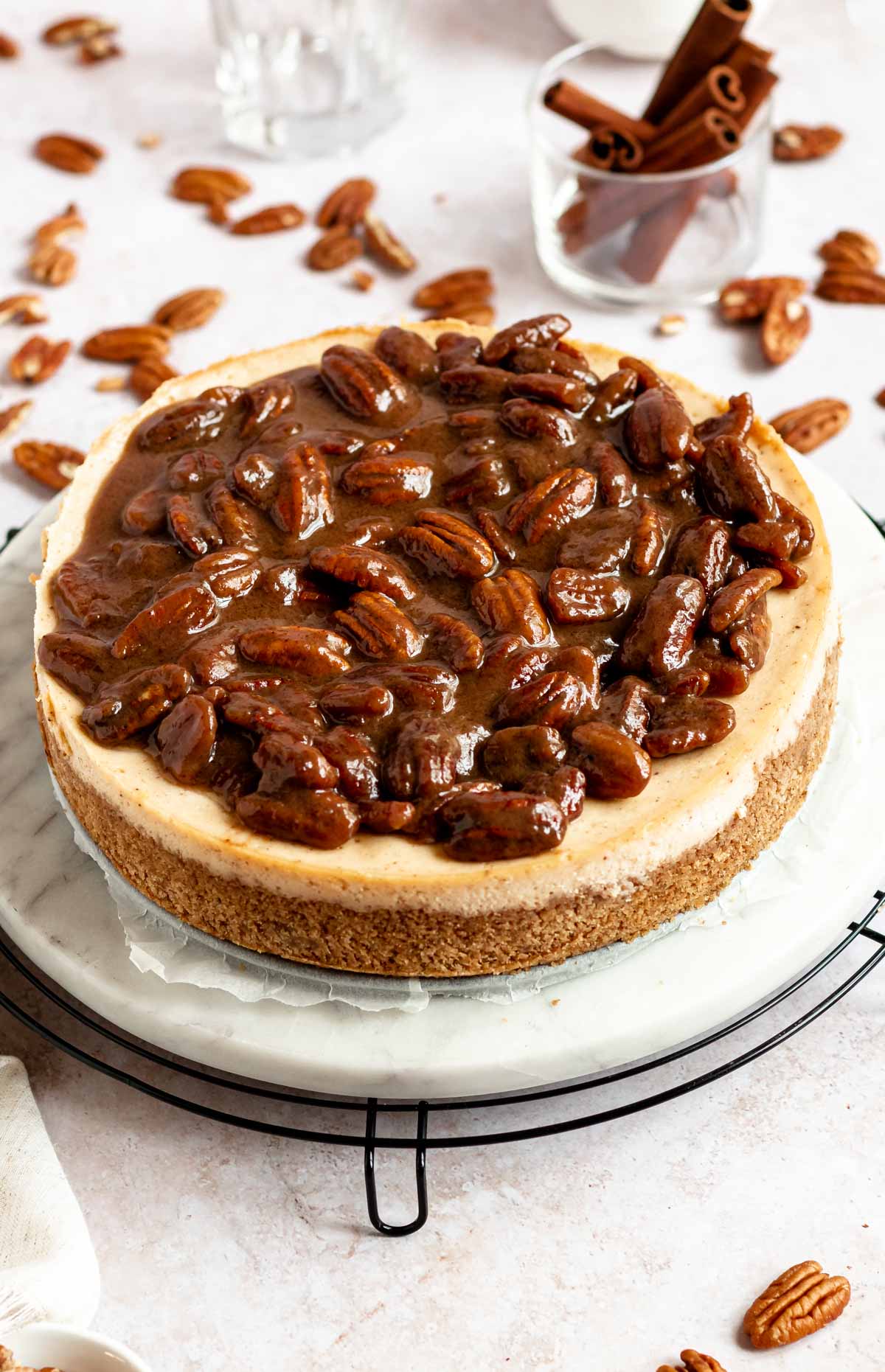 Cheesecake with pecans on a round cooling rack.