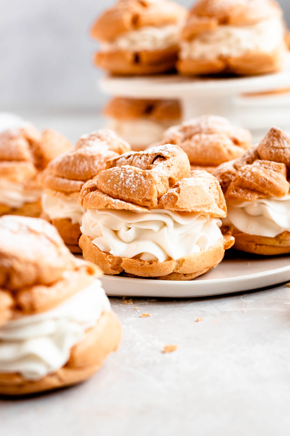 Cream puffs with powder sugar on top on a white plate.