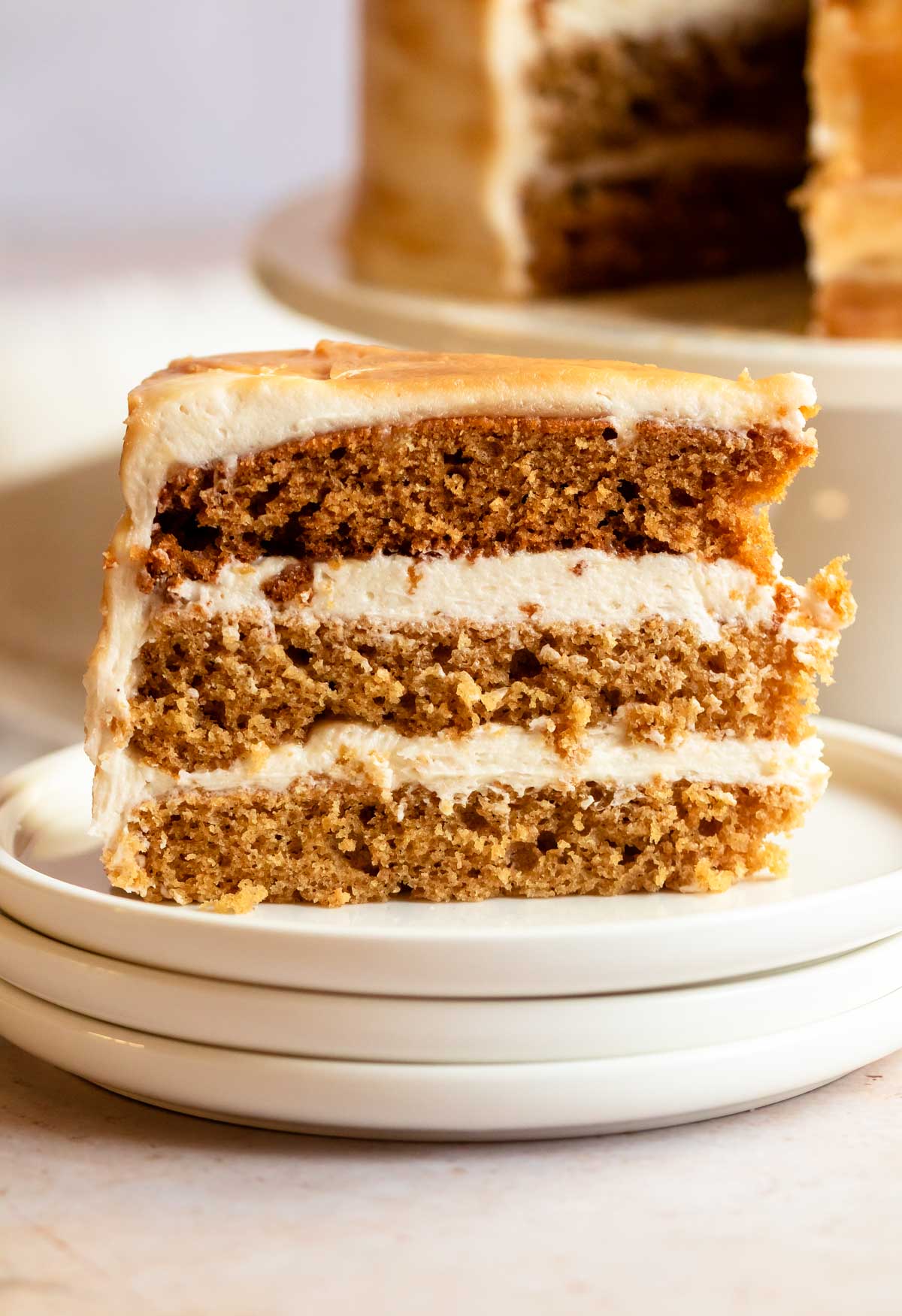 Slice of butterscotch cake on a stack of white plates.