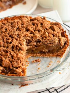 Slice missing from an apple pie with graham cracker crust.