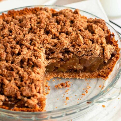 Slice missing from an apple pie with graham cracker crust.