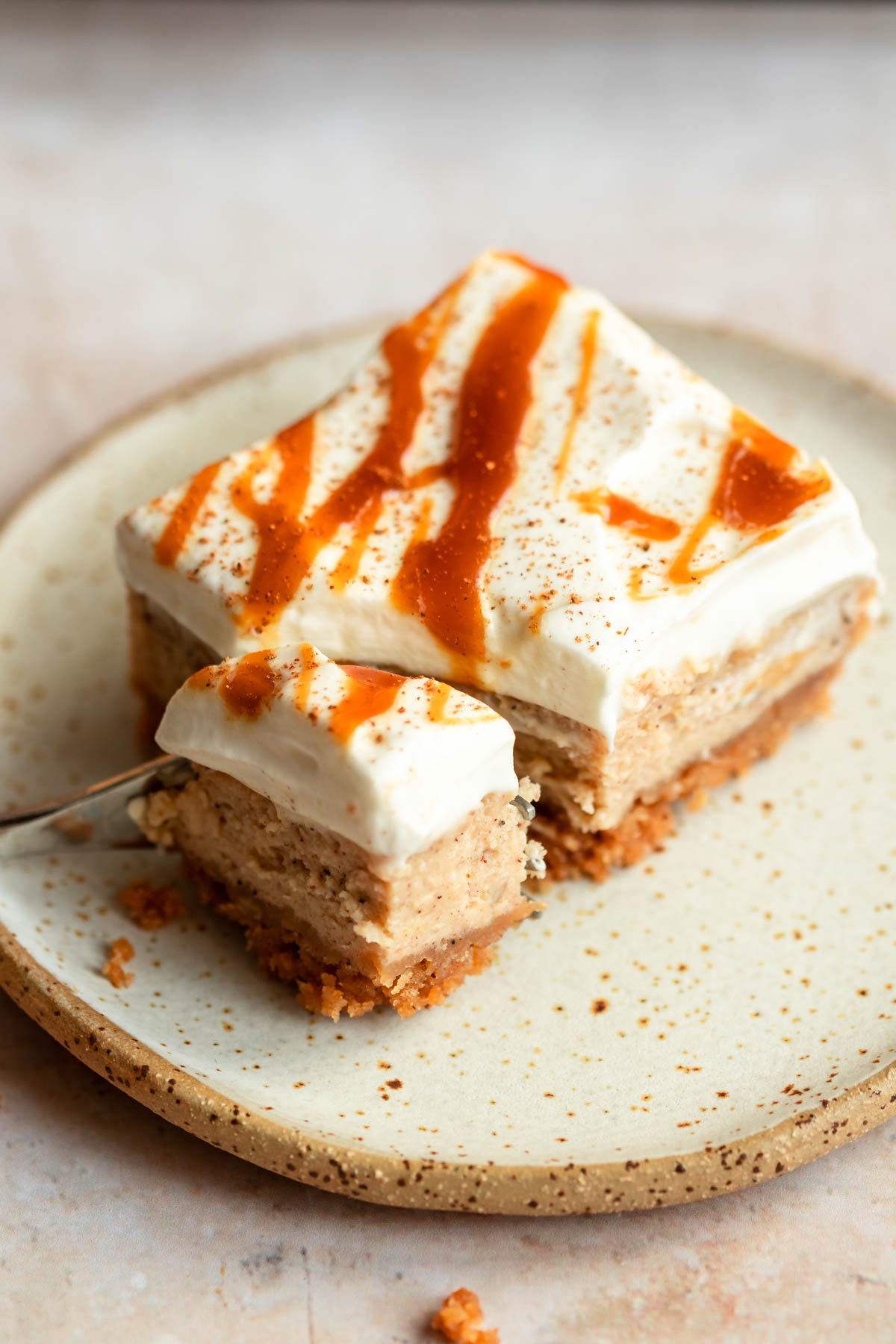 Slice of pumpkin cheesecake bar on a plate with a fork.