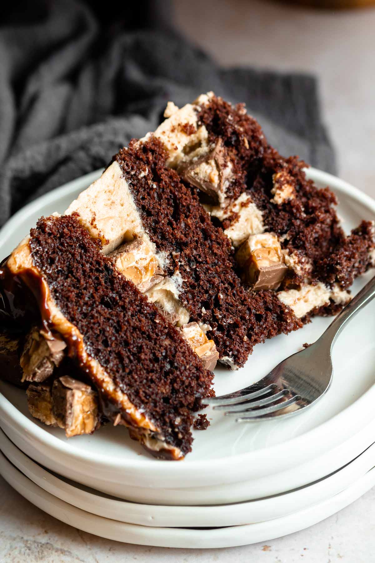 Slice of snickers cake on a stack of white plates.