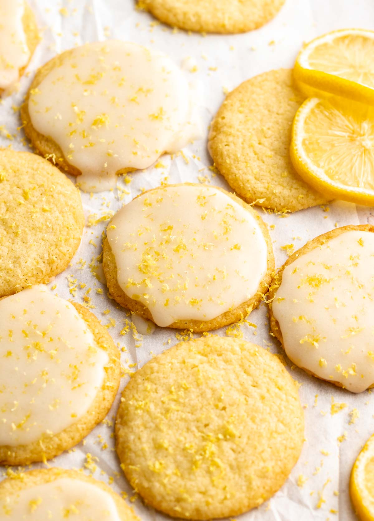 Cookies on a parchment paper with glaze and lemon zest on top.
