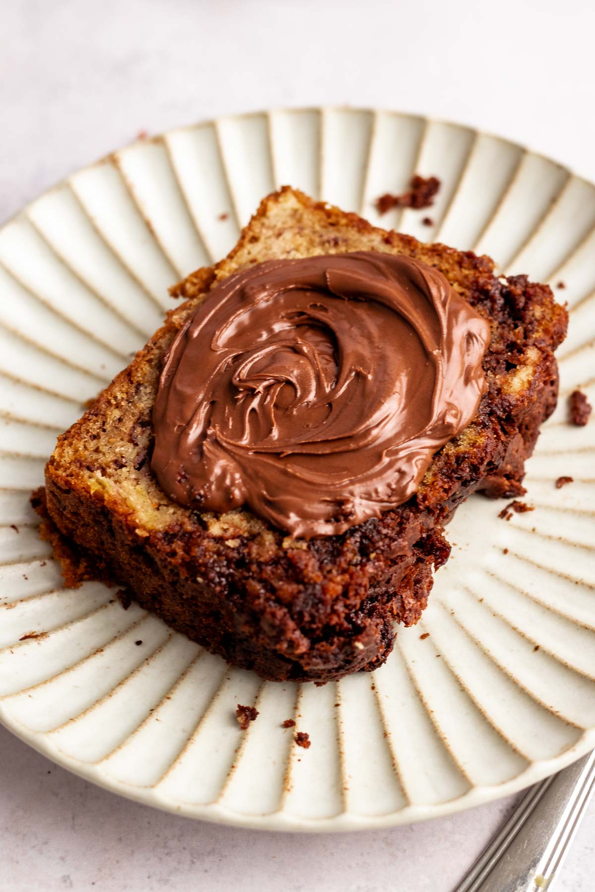 Close up shot of a slice of nutella banana bread with nutella on top.