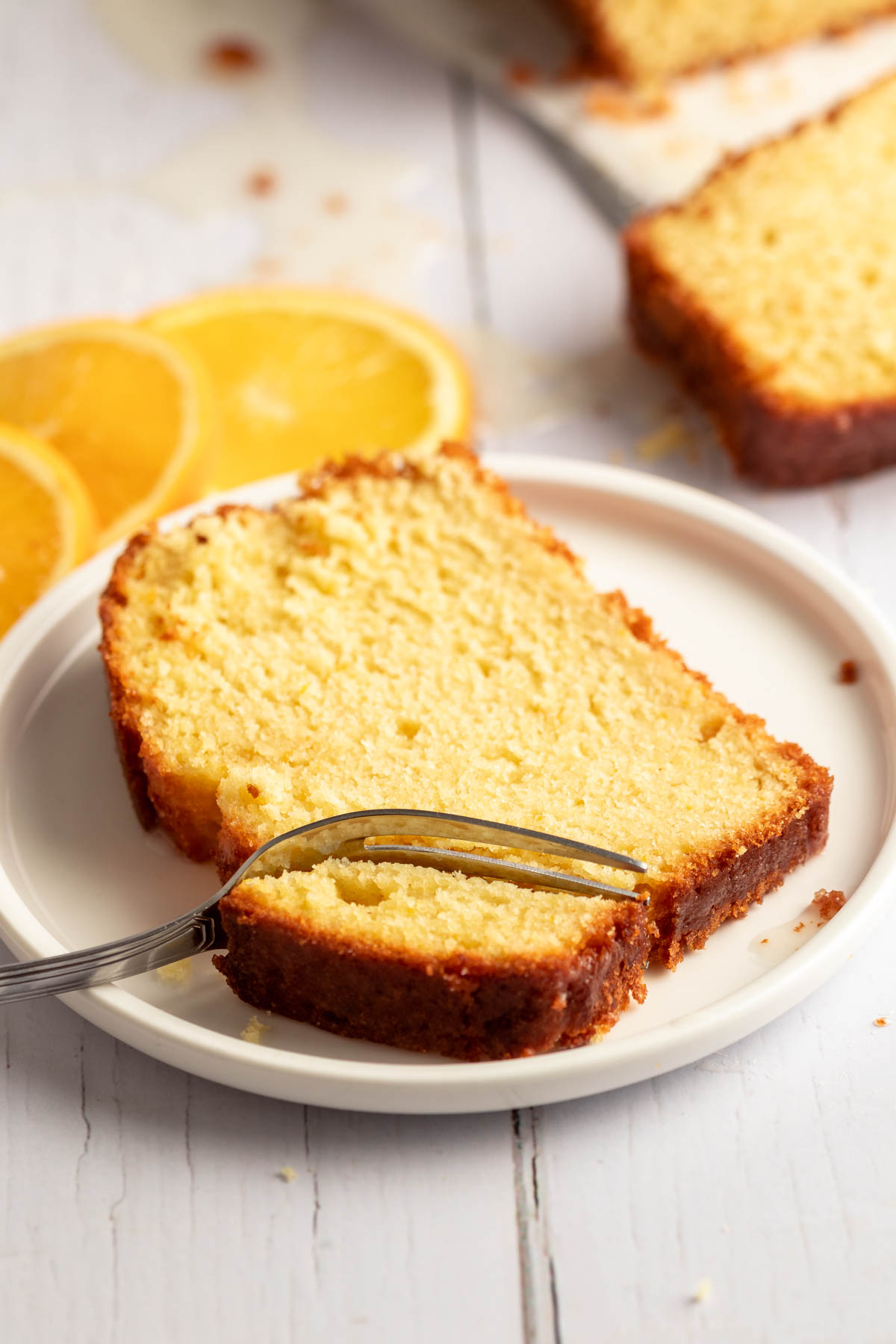 Slice of pound cake on a plate with a fork inserted into the slice.
