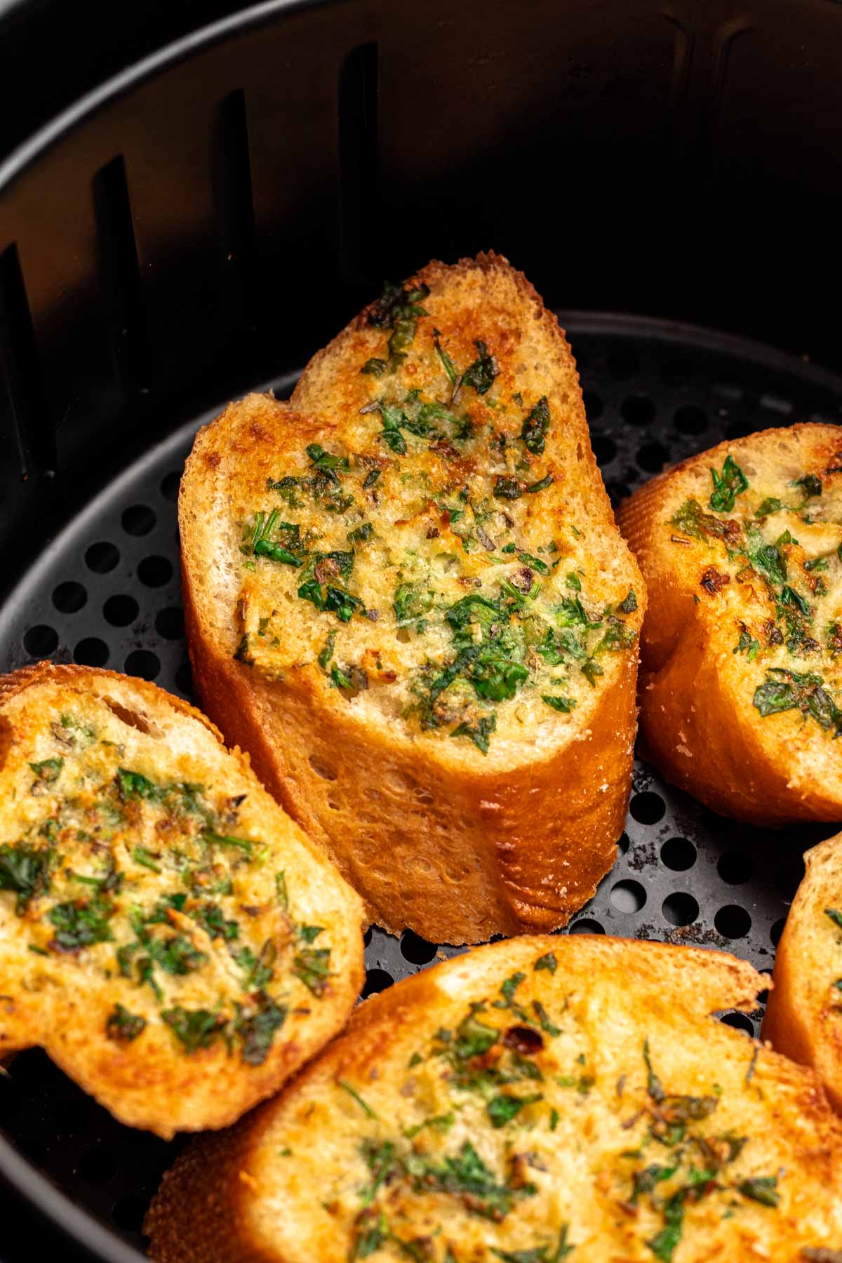 Close up of air fryer garlic bread in an air fryer basket.