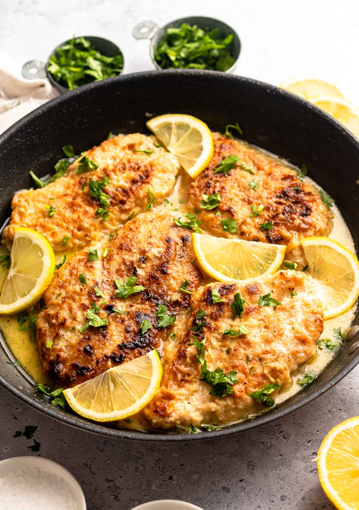 Chicken in a pan with butter lemon sauce.