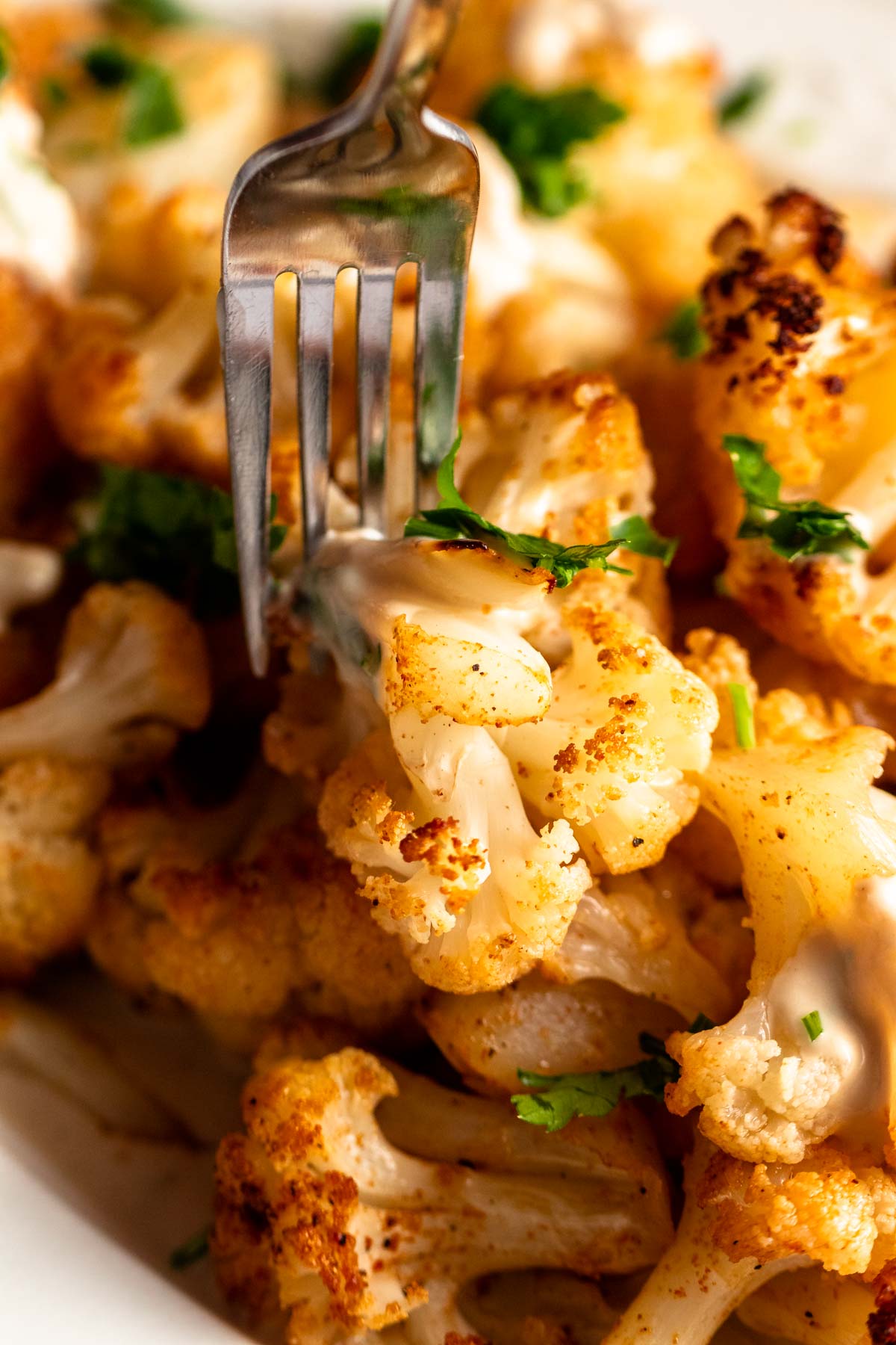 Fork inserted into a piece of roasted cauliflower.