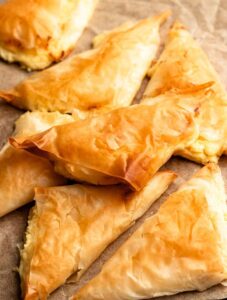 Pile of tiropita on a brown parchment paper.