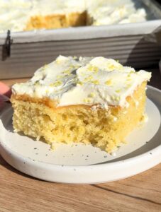 Slice of lemon poke cake with a bite missing.
