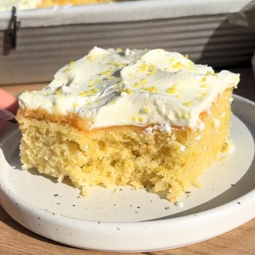 Slice of lemon poke cake with a bite missing.