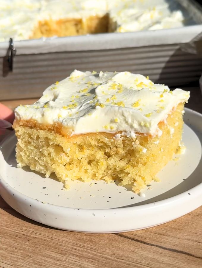 Slice of lemon poke cake with a bite missing.