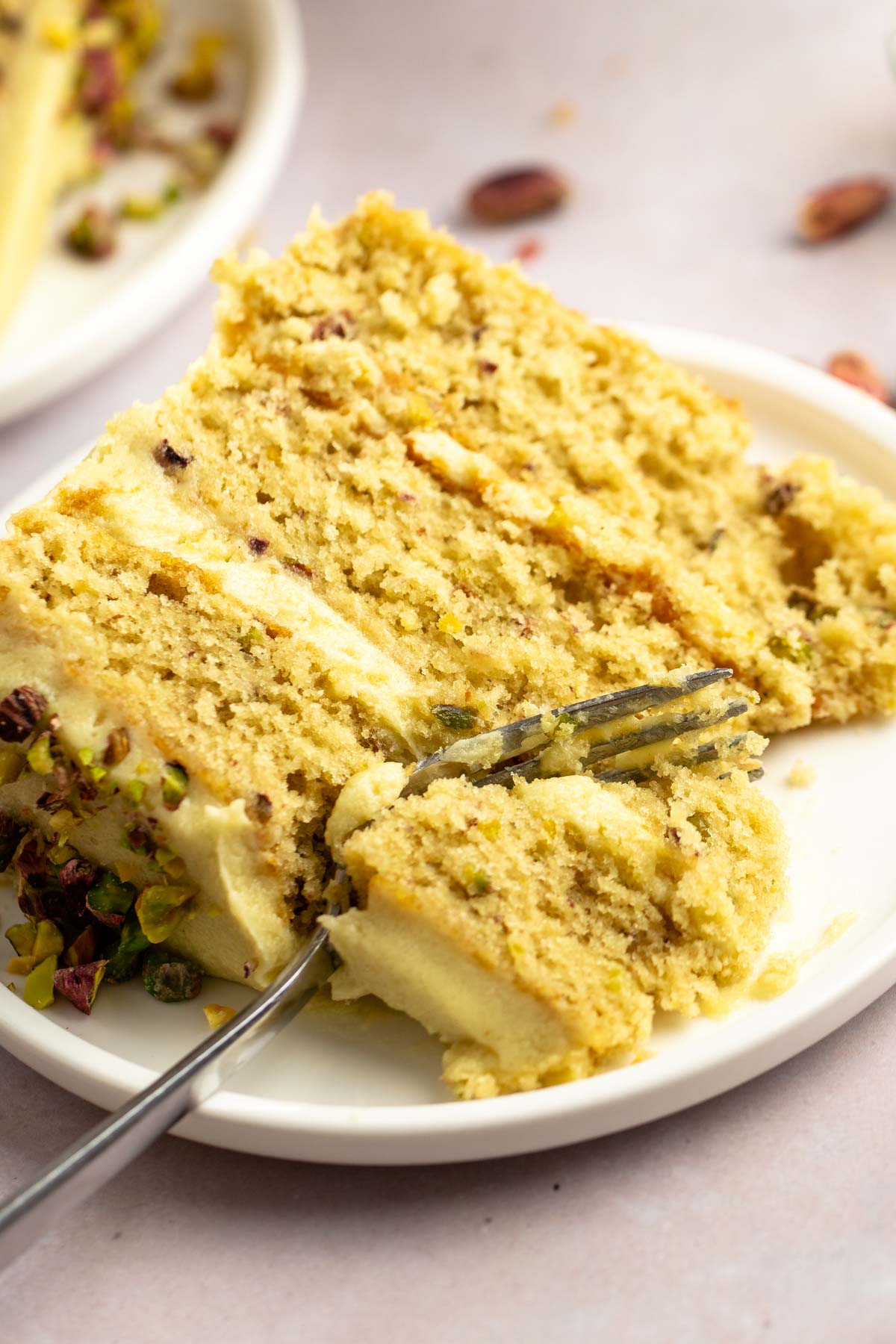 Slice of pistachio cake with a fork inserted into the slice.