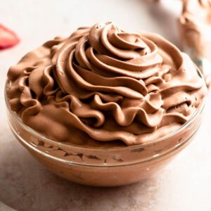 Chocolate whipped cream frosting in a glass bowl.