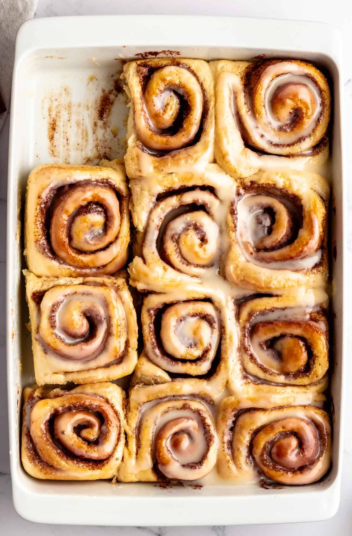 Top of a pan with cinnamon rolls with one missing.