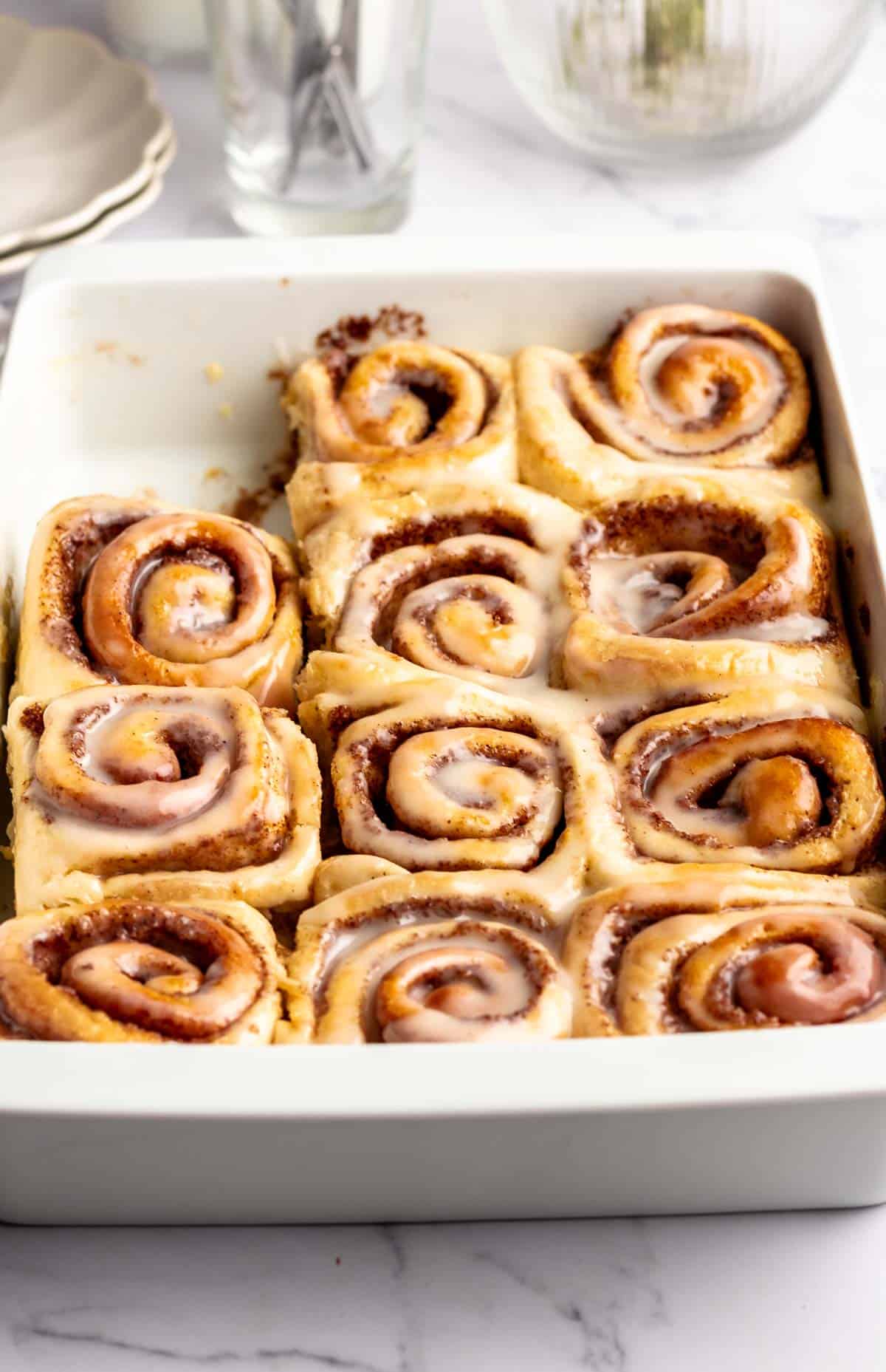 Cinnamon rolls with heavy cream in a baking pan.