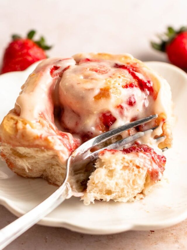 Strawberry cinnamon roll on a plate with a fork.