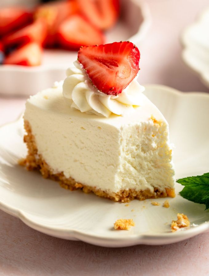Slice of a no bake cheesecake with a strawberry on top.